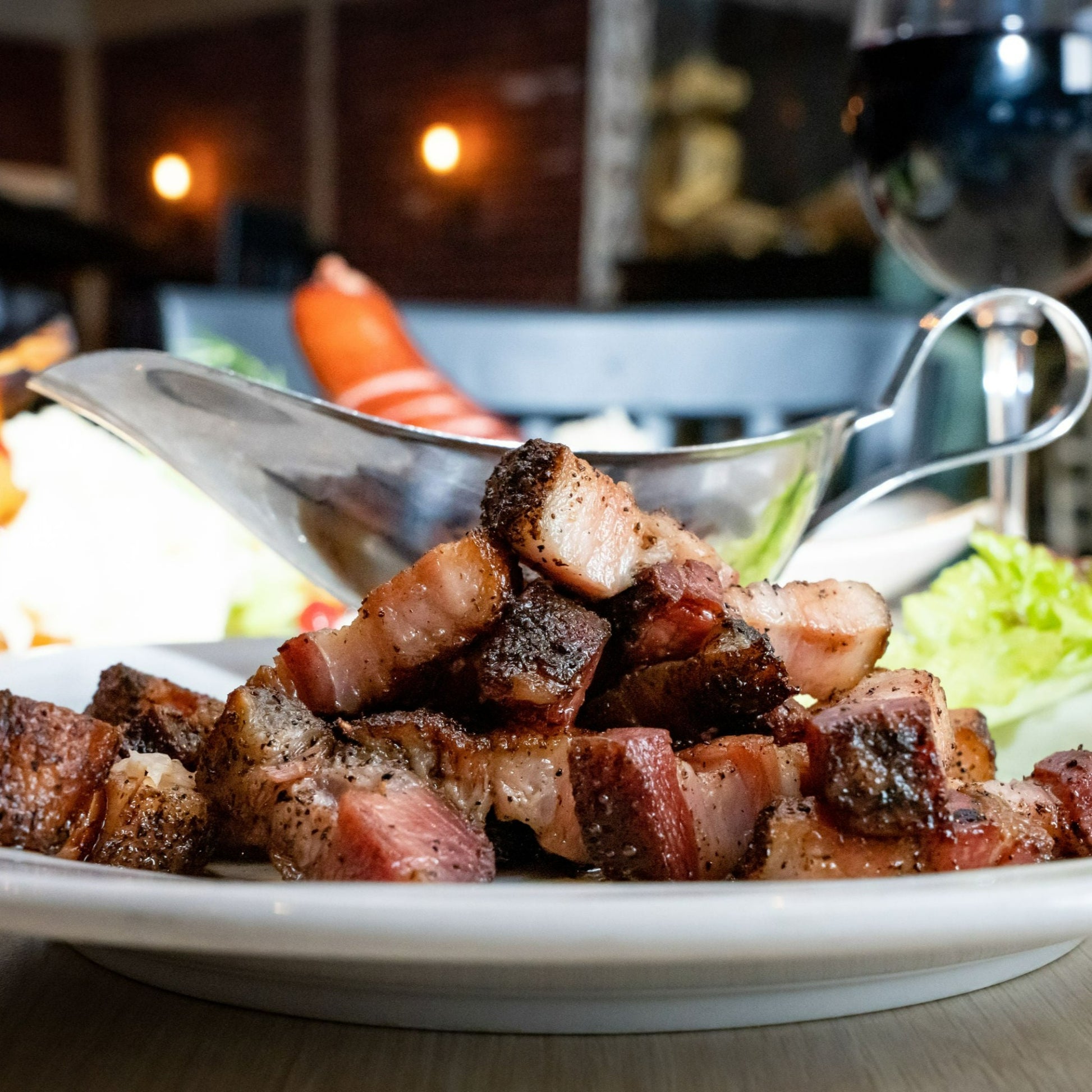 bacon croutons on plate paired with glass of red wine and BBQ sauce