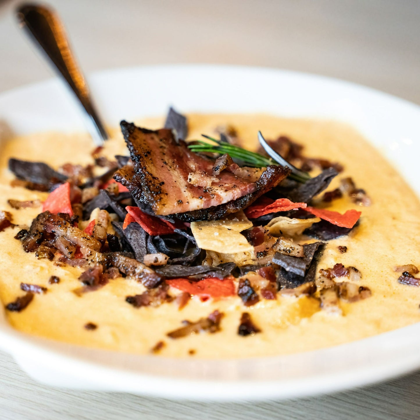 bowl of taco soup topped with crushed tortillas and bacon